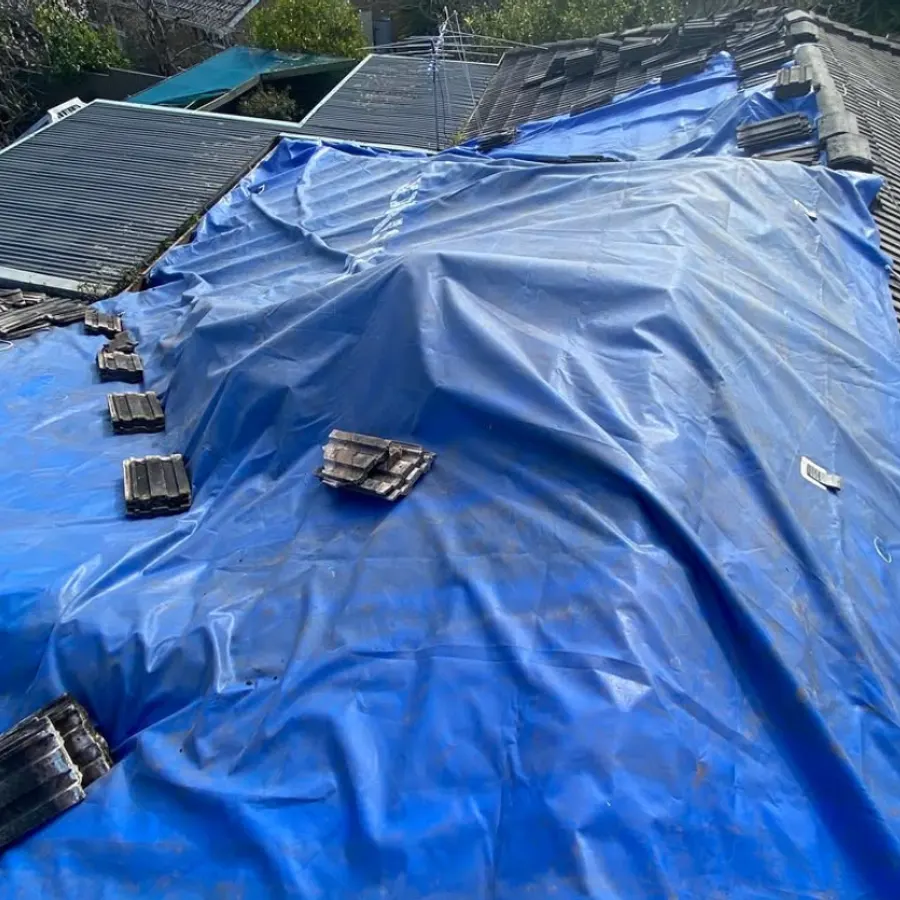 Emergency tarpaulin make-safe on a storm-damaged roof