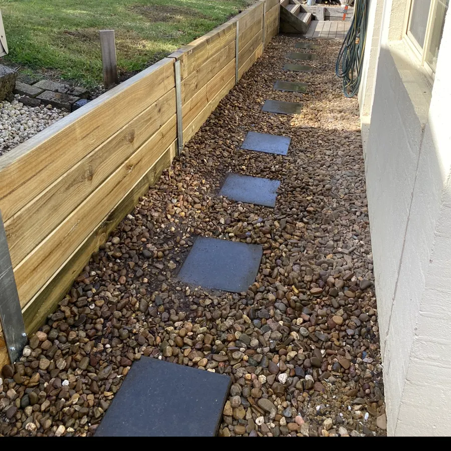 Timber retaining wall beside a pebble path and stepping stones